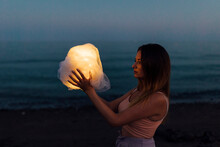 Woman Holding Ball Of Cloth With Light Simulating Moon At Night