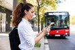 © Westend61 - Businesswoman using smart phone standing in front of bus