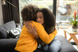 An African-American female psychotherapist comforts the teenage female patient by hugging her. Both of them have the afro hairstyle.