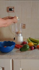 Sticker - Hand preparing a homemade smoothie with various fruit