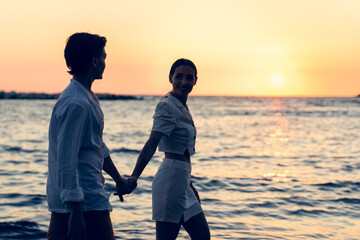 Photoshoot of young helthy beautiful caucasian couple, boy and girl, dating at the beach - Man and woman lovers having fun in holidays walking near the ocean in a sunny day