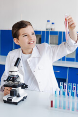 Canvas Print - happy boy looking at test tube near microscope in chemical laboratory.