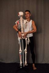 Wall Mural - A man in a white T-shirt studies the structure of the human skeleton