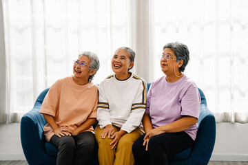 Asian older friends laughing, talking, relaxing and sitting on couch in living room, Lifestyle of happy retired women