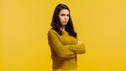 Wall Mural - offended young woman in autumnal sweater standing with crossed arms isolated on yellow