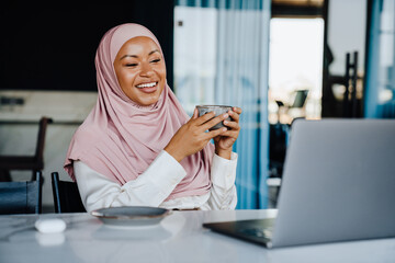 Wall Mural - Muslim young businesswoman drinking coffee while working in office