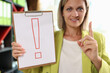 Woman holding clipboard with red exclamation point