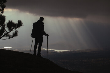 Wall Mural - The silhouette of a man in the mountains who stands on top with the light of the sun