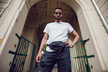 Wall Mural - Stylish african american man in white blank t-shirt and sunglasses. Mock-up.