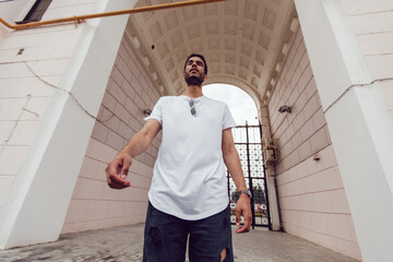 Wall Mural - African american man in a white blank t-shirt walks down the street. Mock-up.