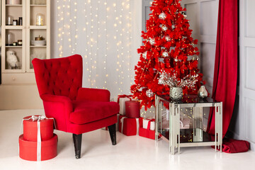 Wall Mural - Stylish Christmas interior with a soft red arm-chair and red christmas tree on background of garland lights. Comfort home. 