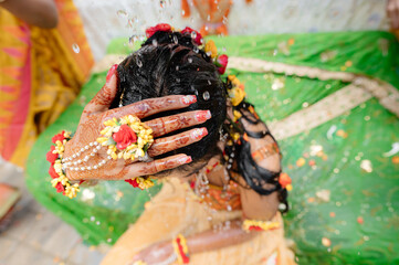 Wall Mural - Process of wedding Indian ceremony. Brunette girl in traditional dress with accessory washing her hair under splashing water