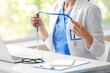 © Pixel-Shot - Female doctor or nurse holding stethoscope at desk with laptop in medical office, closeup healthcare professional in white coat and blue scrubs during consultation or telemedicine