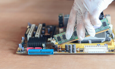 The technician is installing random access memory into the PC motherboard computer.
