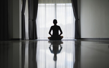 Silhouette of young woman meditating at home. Men practicing yoga indoors. Relaxation, body care, meditation, balance, fitness,  workout, recreation concept,  pray.