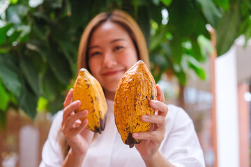 A young woman holding and showing a Cocoa pod