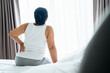 © Suriyawut - Adult Asian woman is sitting on the bed and holding her lower back suffering from injured back. Health care and back pain concept.