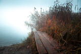 Fototapeta  - Jesień, mgła, jezioro i kolorowe trawy. Klimatyczny, jesienny poranek w Krakowie, na Bagrach. Autumn, fog, lake and colorful leaves. An atmospheric, autumn morning in Krakow. Pomost, kładka