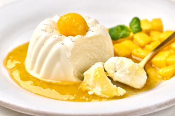 Wall Mural - Macro spoon with piece of homemade panna cotta with natural vanilla pod, mango syrup and mint, selective focus