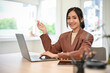 © bongkarn - Beautiful Asian businesswoman working at her desk, smiling and looking at camera.