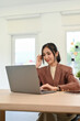 © bongkarn - Portrait, Attractive Asian businesswoman in casual suit working on her tasks on laptop