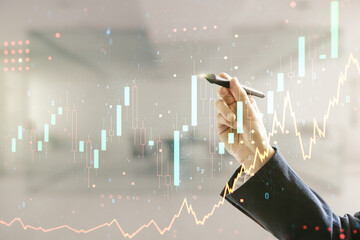 Multi exposure of trader hand with pen working with virtual abstract financial graph interface on blurred office background, financial and trading concept