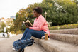 © PintoArt - Curvy afro woman reading book outdoors