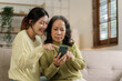 © NanSan - Mature asian mom with daughter on video call to parents, loving mother day concept.