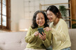 © NanSan - Mature asian mom with daughter on video call to parents, loving mother day concept.
