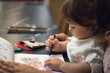 © TenWit - An young adorable toddler boy sat with his mother drawing with crayons in a coloring-in book