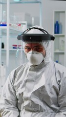 Wall Mural - Vertical video: Close up of tired chemist man doctor in coverall working in scientific equipped laboratory. Scientist working with various bacteria, tissue and blood samples, pharmaceutical research