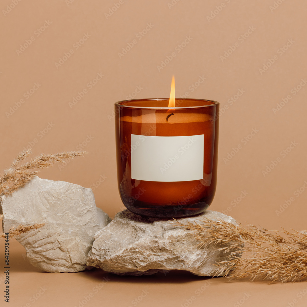 Burning handmade candle in a glass jar with empty label mockup, soy ...