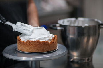 pastry chef designer filling a pie crust with lemon flavour meringue mousse cheese cream with spatula