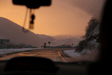 Road By Mountains Against Sky During Winter At Sunset Seen Through Car Windshield