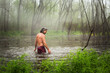© Cavan Images - Atchafalaya River, Louisiana, USA. A man in a bathing suit wades through a foggy swamp lagoon.