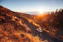 A Car Runs On An Empty Mountain Road At Sunset