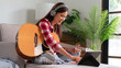Hobby concept, Young asian woman wear earphone learning music on tablet and playing acoustic guitar