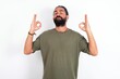 © Jihan - young bearded hispanic man wearing green t-shirt over white background relax and smiling with eyes closed doing meditation gesture with fingers. Yoga concept.