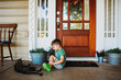 © Cavan Images - Young boy looking at pet cat on front porch in summer time