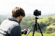 © Cavan Images - Person using smartphone app to control camera on tripod outdoors