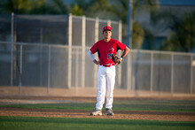 Teen Baseball Player In Red Uniform Standing In The Infield