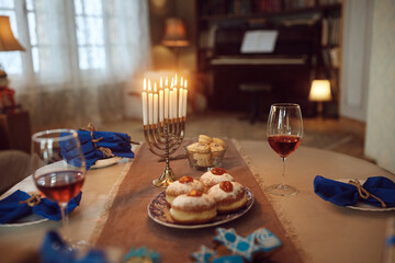 Menorah with lit candles on dinning table decorated for Hanukkah celebration