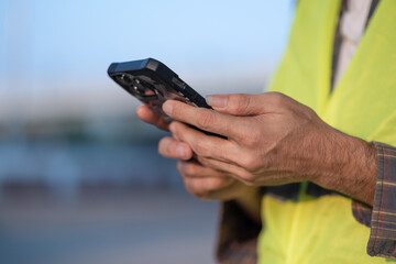 Close up male construction worker using mobile phone