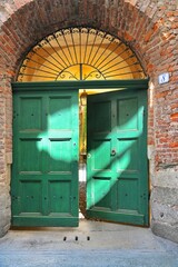 Wall Mural - Ancient portal made of green wooden door and wrought iron on rustic red bricks wall