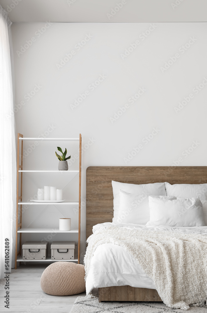 Interior of modern bedroom with big bed and shelving unit