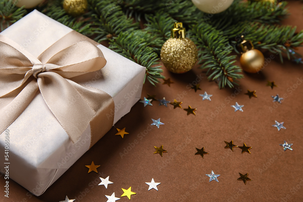 Composition with fir branches, Christmas balls and gift on color background, closeup