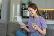 © kucherav - Happy young woman using mobile app to paying household bill, taxes or insurance use secure internet banking. Female holding bank letter reading good news, closed her bank loan