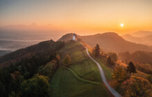 Aerial Drone View Of Small Beautiful Church On Top Of A Mountain In Slovenia At Dawn. Beautiful Autumn Morning Landscape