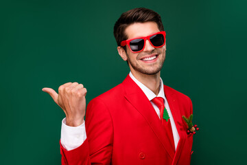 Sticker - Photo of pretty sweet santa claus guy dressed red jacket glasses pointing back empty space isolated green color background