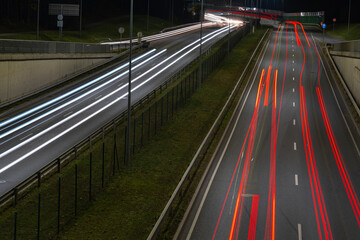 Cars blurred lighting traces on night on roadway from Riga to resort city Jurmala. Shot from bridge over way.